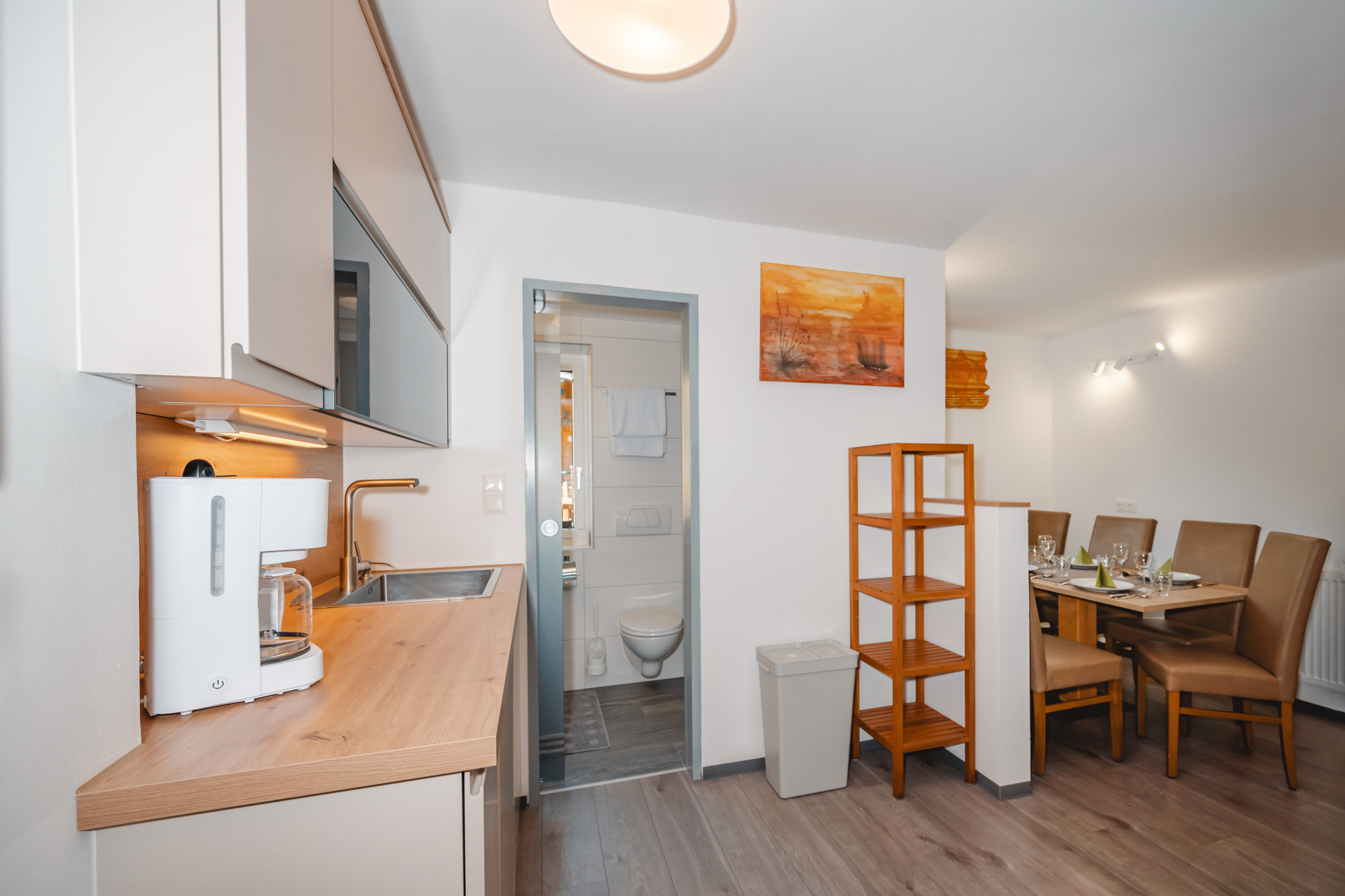 Monteur-Zimmer - Fernseher - Wagrain - Eine moderne Küche mit Holzarbeitsplatte und einem Essbereich. Der Raum ist hell und freundlich gestaltet. Man sieht die Spülmaschine, Kaffeemaschiene und den Eingang in das Badzimmer getrennt durch eine Glasschiebetür. - Haus Ortsblick