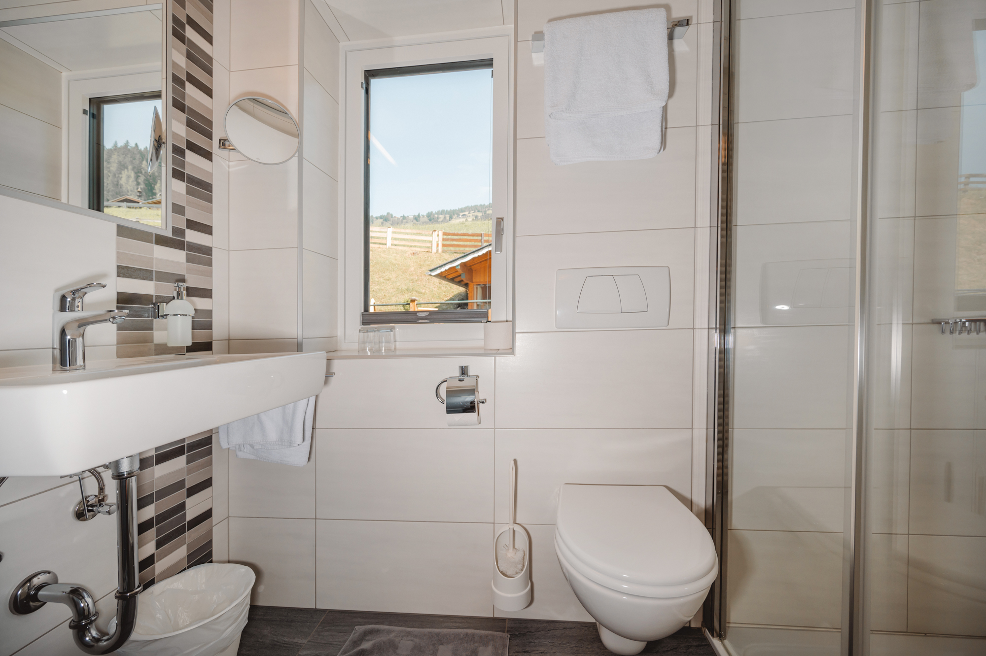 Monteur-Zimmer - Fernseher - Wagrain - Ein helles Badezimmer mit modernen Fliesen und einem großen Fenster. Die Einrichtung besteht aus einem Waschbecken, einer Dusche und einer Toilette. - Haus Ortsblick
