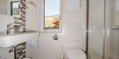 Monteur-Zimmer - Österreich - Ein helles Badezimmer mit modernen Fliesen und einem großen Fenster. Die Einrichtung besteht aus einem Waschbecken, einer Dusche und einer Toilette. - Haus Ortsblick