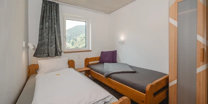 Monteur-Zimmer - Österreich - Ein einfaches Schlafzimmer mit zwei Betten und einem Fenster. Die Wände sind hell und es gibt einen Schrank aus Holz. - Haus Ortsblick
