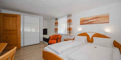 Monteur-Zimmer - Österreich - Ein großes Schlafzimmer mit einem Doppelbett und einem Einzelbett sowie hellem Holzmobiliar. Die großen Fenster sorgen für viel Tageslicht und eine einladende Atmosphäre. Ein großer Schrank bietet Platz für Ihre Kleidung. - Haus Ortsblick