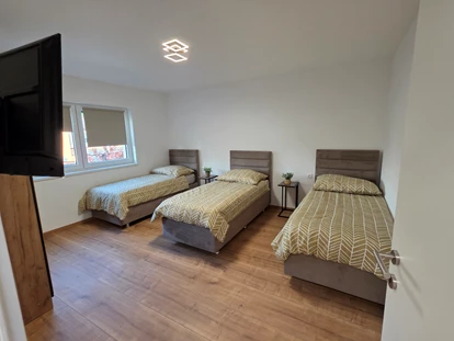 Monteur-Zimmer - Küche - Wien-Stadt - Schlafzimmer 3 ist mit drei komfortablen Boxspringbetten, einem TV, einem Kleiderschrank sowie Steckdosen und Ablagemöglichkeiten für Handys und Wasser ausgestattet - Imperial Premium Mouteurzimmer