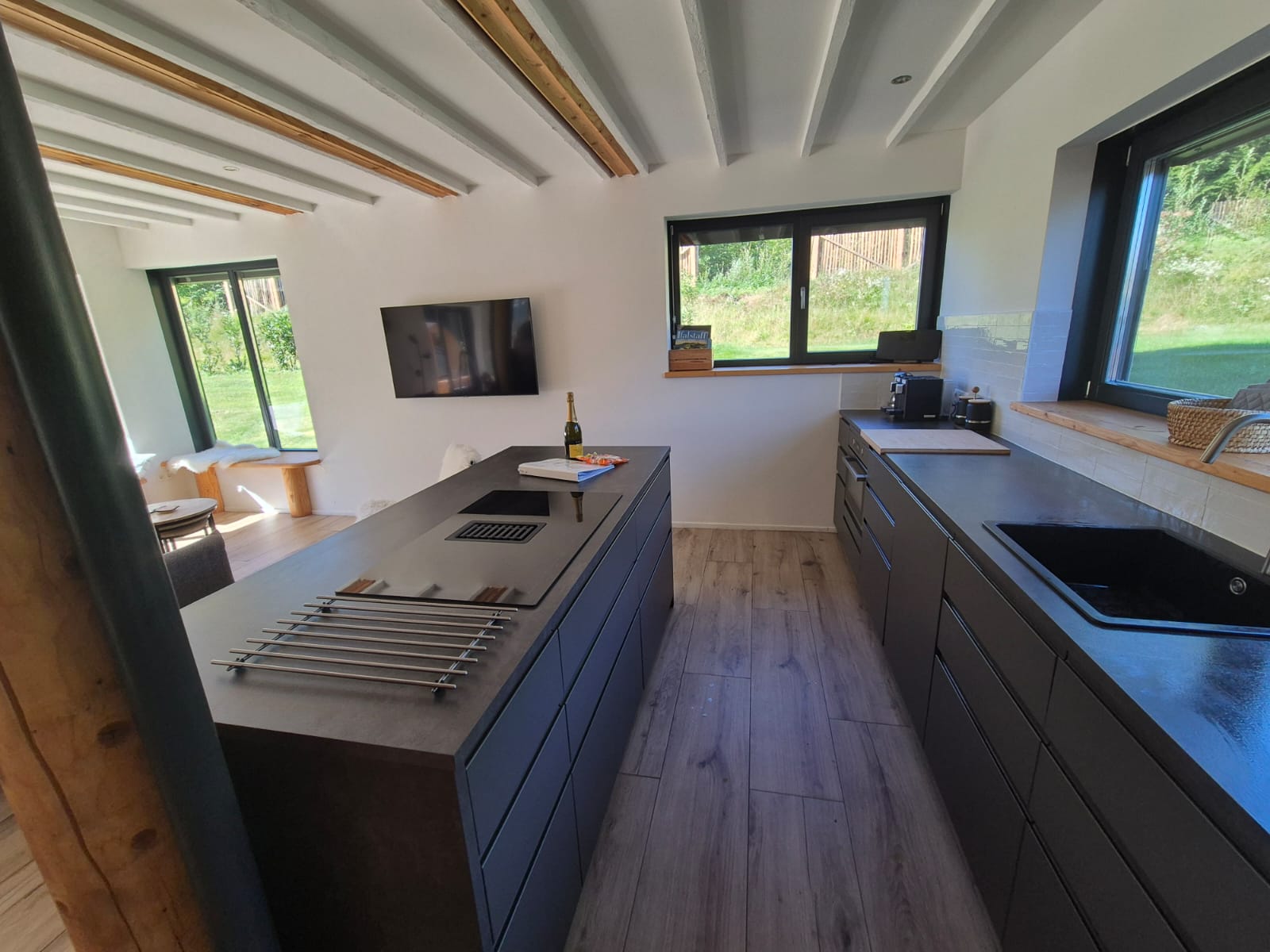 MonteurZimmer: Küche mit Kochinsel und links wohnbereich mit Fernseher  - Trahütti Premium Lodges 