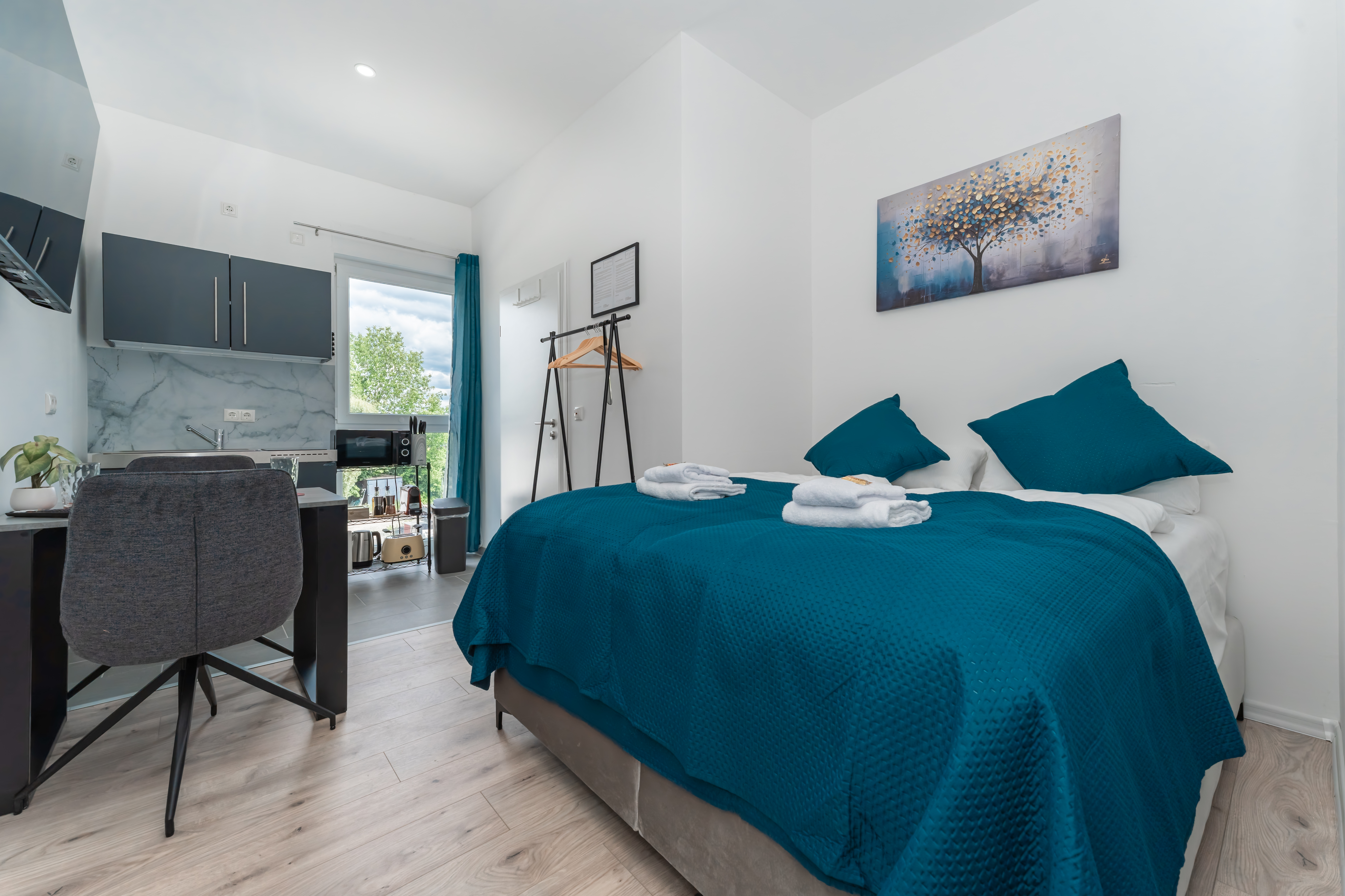 MonteurZimmer: Zimmeransicht Doppelzimmer mit Boxspringbett und Küche sowie Essbereich - Komfortable Apartments